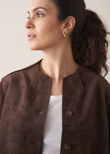 Woman wearing a brown faux suede jacket and dark jeans