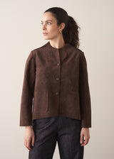 Woman wearing a brown faux suede jacket and dark jeans