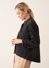 Woman wearing black faux suede boxy jacket and beige cropped trousers