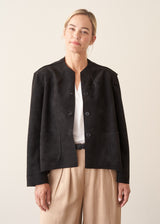 Woman wearing black faux suede boxy jacket and beige cropped trousers