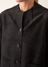 Woman wearing black faux suede boxy jacket and beige cropped trousers