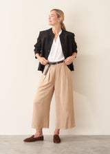 Woman wearing black faux suede boxy jacket and beige cropped trousers