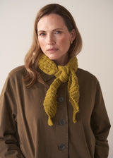 Woman wearing a olive knitted neckscarf with brown trench coat