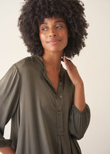 Woman wearing a khaki satin midi dress with khaki strappy sandals.