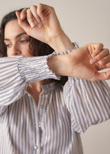 Woman wearing striped cotton shirt with ruched sleeves and frilled collar