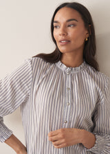 Woman wearing a striped shirt against a plain background