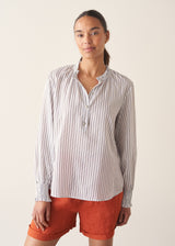 Woman wearing white and blue stripe light shirt with ruffle collar and red linen shorts