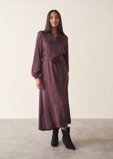 Woman wearing long sleeve plum satin button up dress with waist tie