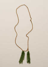 A long, chunky chain necklace with two pendants made of colourful green crystal strands, photographed on a beige background