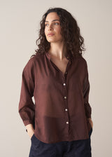 Woman wearing a sheer brown cotton shirt with blue jeans