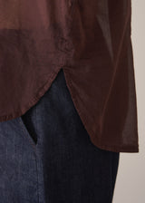 Woman wearing a sheer brown cotton shirt with blue jeans