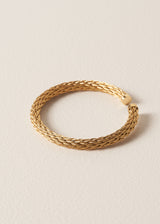 Gold rope style bangle on a beige background