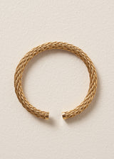 Gold rope style bangle on a beige background